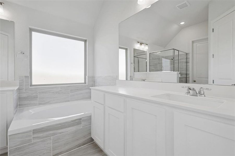 Bathroom featuring vanity, lofted ceiling, and independent shower and bath