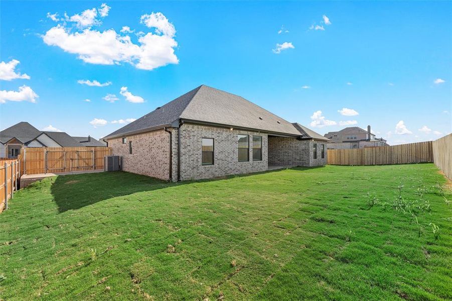 Rear view of house with a fenced backyard, brick siding, a patio area, and roof with shingles Rear view of house with a fenced backyard, brick siding, a patio area, and roof with shingles