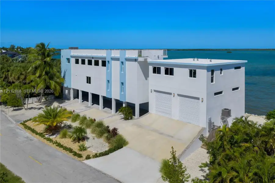 Contemporary multi-level waterfront residence featuring a concrete exterior, dual-car garage, and roof deck Contemporary multi-level waterfront residence featuring a concrete exterior, dual-car garage, and roof deck