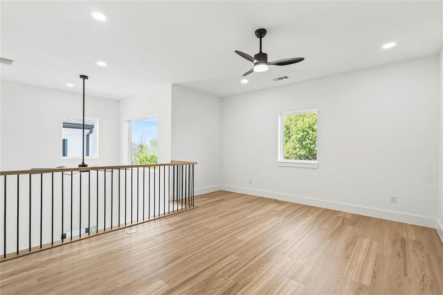 Empty room featuring light wood-style flooring, ceiling fan, healthy amount of natural light, and recessed lighting