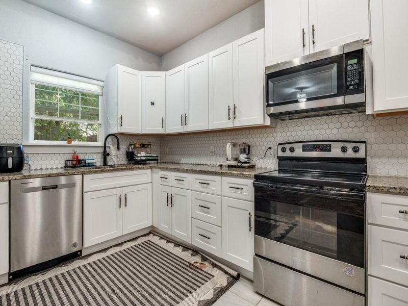 Kitchen featuring stainless steel appliances, tasteful backsplash, white cabinetry, light stone countertops, and recessed lighting Kitchen featuring stainless steel appliances, tasteful backsplash, white cabinetry, light stone countertops, and recessed lighting