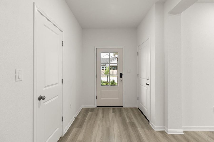 Entryway featuring light-colored flooring, white walls, and a glass-paneled front door