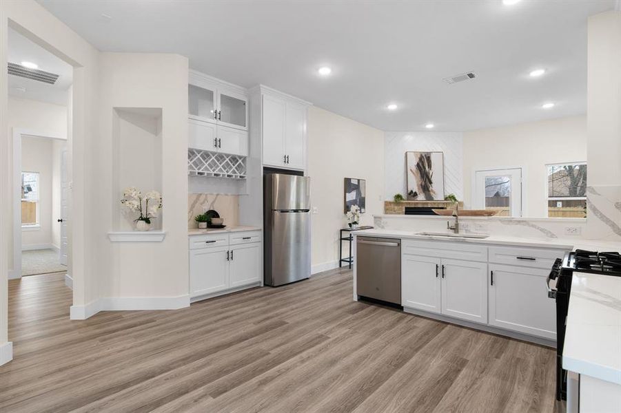 Kitchen with white cabinetry, sink, light hardwood / wood-style floors, and appliances with stainless steel finishes