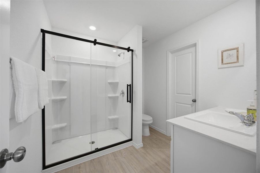 Smooth vinyl flooring and a modern glass-enclosed shower define this clean bathroom space.