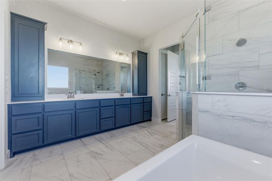Full bath featuring double vanity, a marble finish shower, light marble finish floors, and a tub