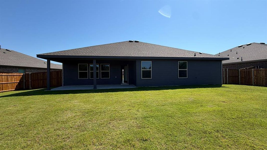 Expansive backyard featuring a covered patio, concrete slab, wood privacy fencing, and a dark-colored exterior Expansive backyard featuring a covered patio, concrete slab, wood privacy fencing, and a dark-colored exterior
