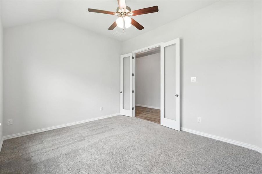 Unfurnished bedroom featuring carpet floors, ceiling fan, and lofted ceiling