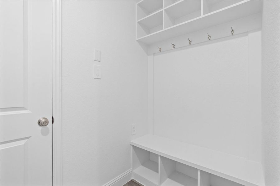 Step into this highly functional and stylish mudroom drop zone, an essential feature for a busy household. The space boasts custom-built white cabinetry and shelving, providing generous storage for coats, bags, and shoes. A comfortable built-in bench offers a convenient spot to sit, while three sleek hooks keep outerwear tidy and accessible. Step into this highly functional and stylish mudroom drop zone, an essential feature for a busy household. The space boasts custom-built white cabinetry and shelving, providing generous storage for coats, bags, and shoes. A comfortable built-in bench offers a convenient spot to sit, while three sleek hooks keep outerwear tidy and accessible.