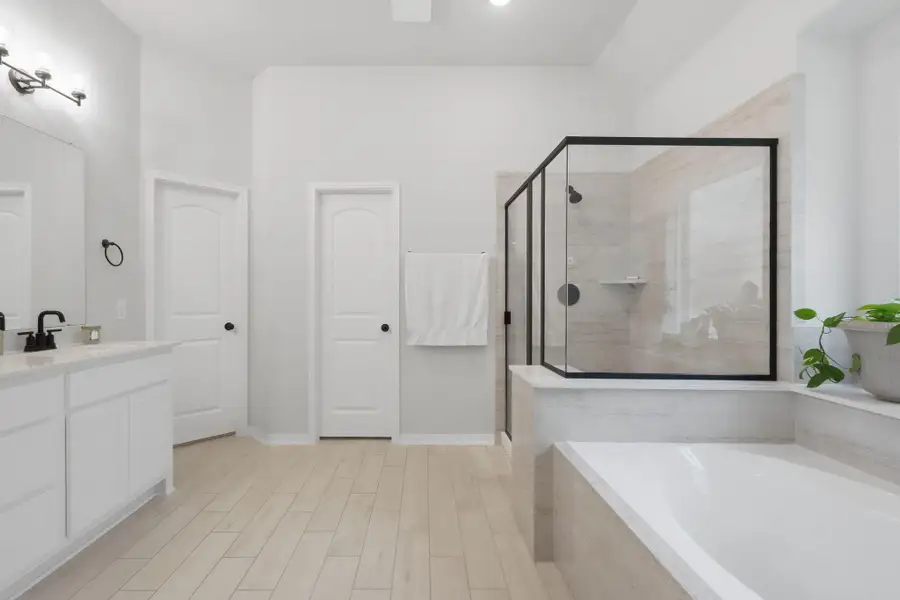 Primary bathroom featuring dual sinks, a soaking tub, and a walk-in shower.