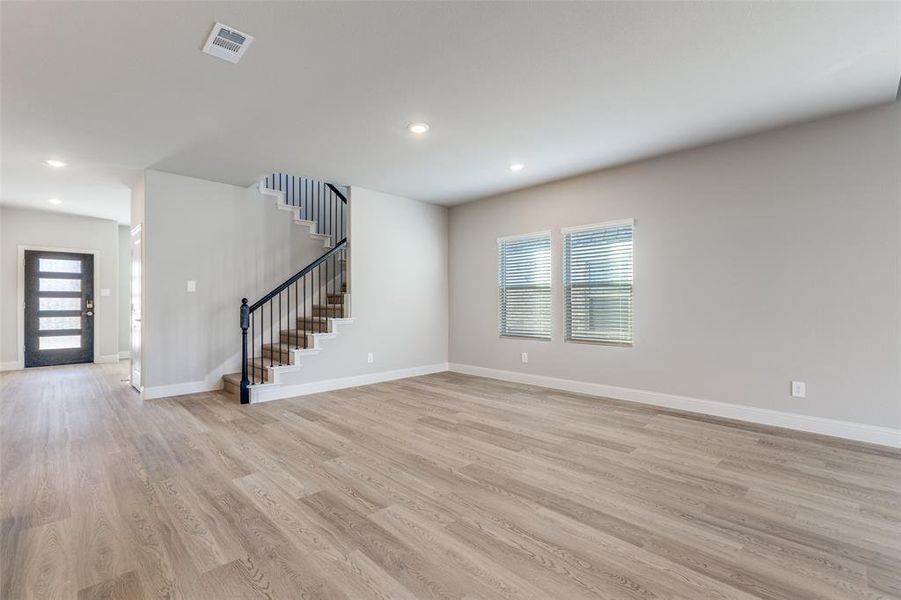 Unfurnished living room featuring light wood-type flooring, stairs, and recessed lighting Unfurnished living room featuring light wood-type flooring, stairs, and recessed lighting