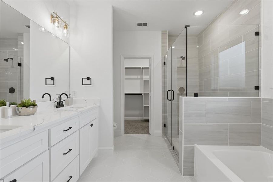 Bathroom with a shower stall, double vanity, light tile patterned floors, a bath, and a walk in closet