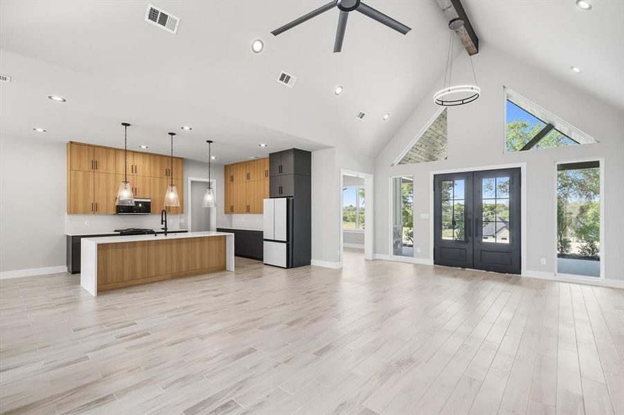 Kitchen featuring decorative light fixtures, open floor plan, high vaulted ceiling, beam ceiling, and an island with sink Kitchen featuring decorative light fixtures, open floor plan, high vaulted ceiling, beam ceiling, and an island with sink
