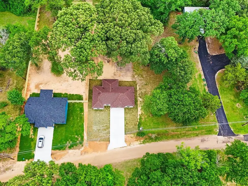 Aerial perspective showcasing two properties with brown and blue rooflines, each featuring a concrete driveway Aerial perspective showcasing two properties with brown and blue rooflines, each featuring a concrete driveway