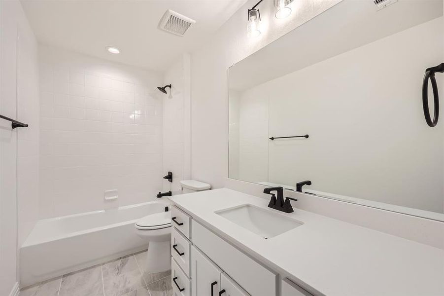 Full bathroom featuring toilet, vanity, and tiled shower / bath