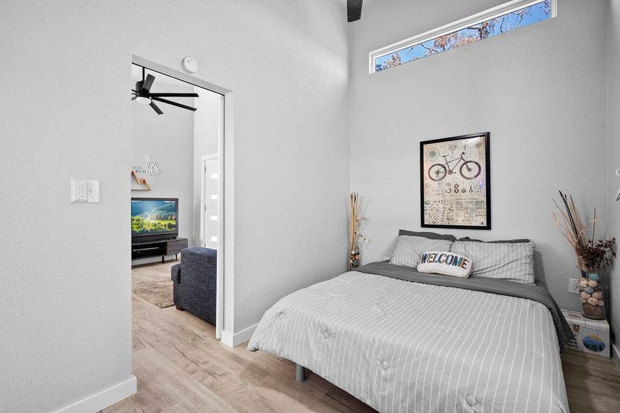 Bedroom with wood finished floors and a towering ceiling.