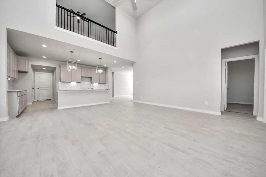 Gather the family and guests together in your lovely living room! Featuring soaring high ceilings, recessed lighting, ceiling fan, custom paint, gorgeous floors, and large windows that provide plenty of natural lighting throughout the day. Sample photo of completed home with similar floor plan. Actual colors and selections may vary.