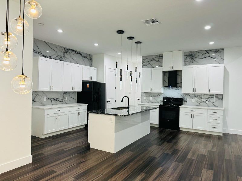 Kitchen with black range with electric cooktop, dark stone counters, white cabinetry, and range hood Kitchen with black range with electric cooktop, dark stone counters, white cabinetry, and range hood