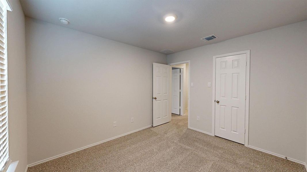 Unfurnished bedroom with light colored carpet and baseboards