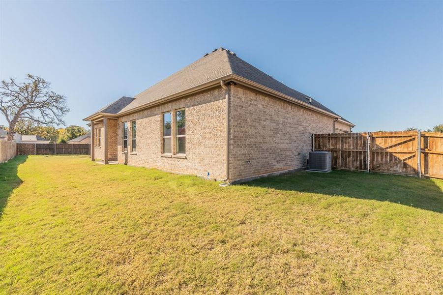 Back of house with central AC unit and a yard