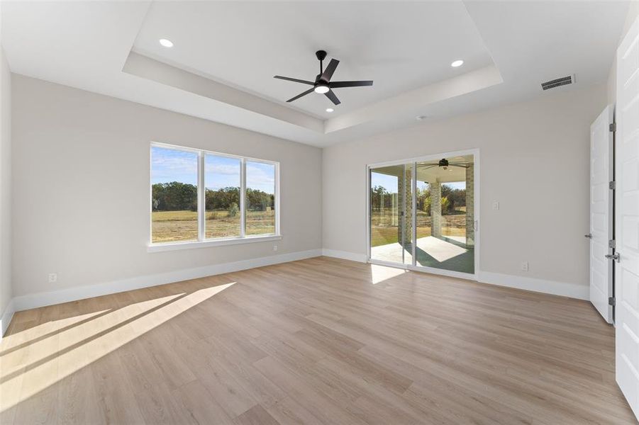 Unfurnished room with light wood-style flooring, ceiling fan, a tray ceiling, and recessed lighting Unfurnished room with light wood-style flooring, ceiling fan, a tray ceiling, and recessed lighting