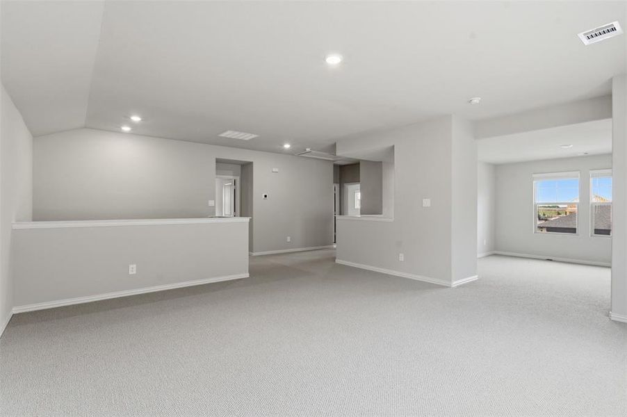 Spacious carpeted interior with recessed lighting, an interior balcony, and windows providing natural light