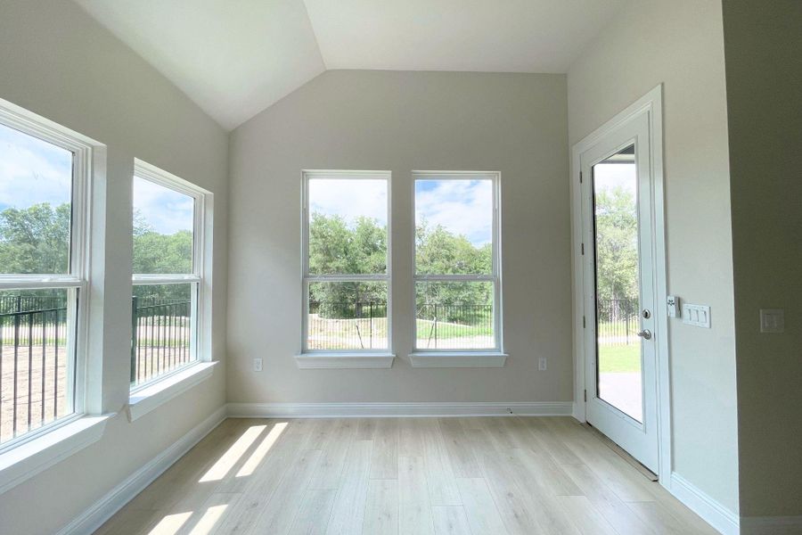 A well-lit room offering views of nature through multiple windows and a glass-paneled door.