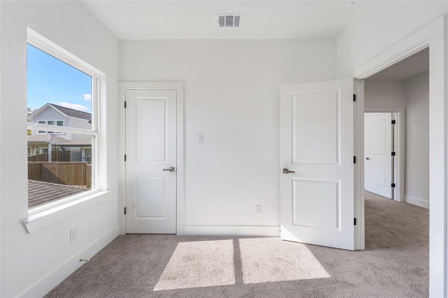 Unfurnished bedroom with light carpet and baseboards