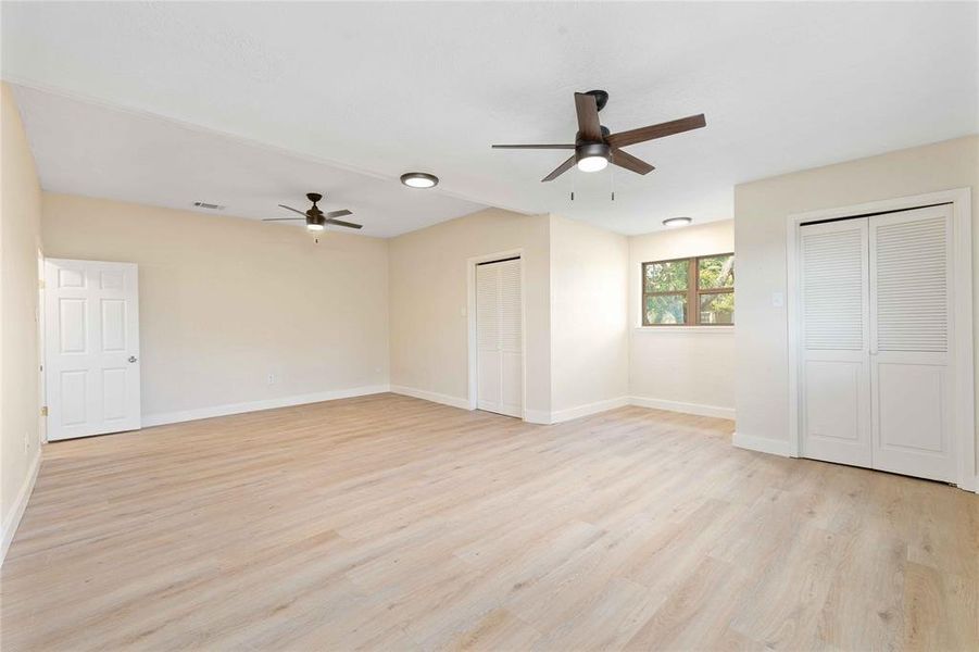 Unfurnished bedroom featuring multiple closets, light wood-type flooring, and a ceiling fan Unfurnished bedroom featuring multiple closets, light wood-type flooring, and a ceiling fan