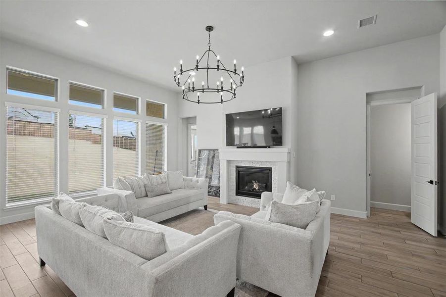 Spacious living area featuring a fireplace with a tiled surround and white mantel, a large multi-paned window wall, and recessed lighting