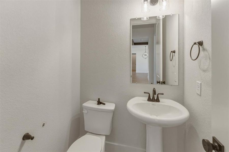 Pedestal sink with a bronze-finish faucet, rectangular mirror, and complementary lighting fixture Pedestal sink with a bronze-finish faucet, rectangular mirror, and complementary lighting fixture