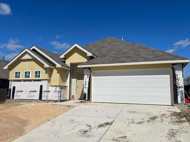 View of front of property featuring stucco siding, an attached garage, driveway, and roof with shingles