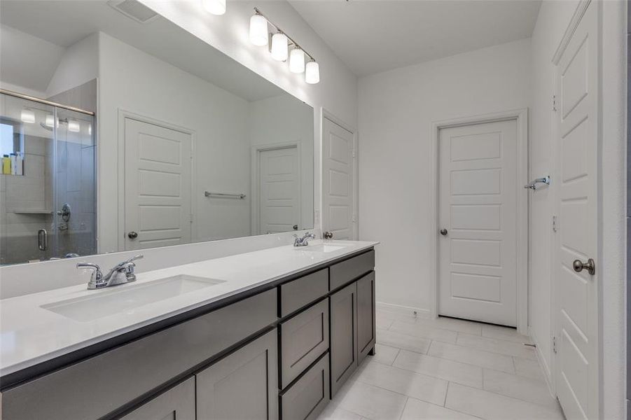 Full bathroom featuring double vanity, a shower stall, and light tile patterned floors