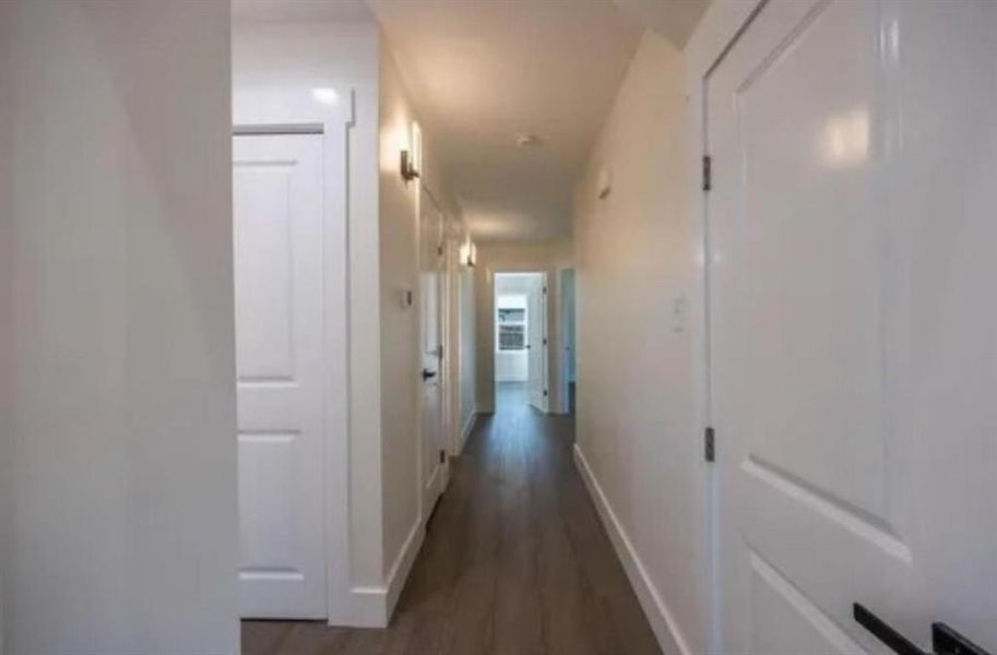 Hallway featuring dark wood-style floors and baseboards