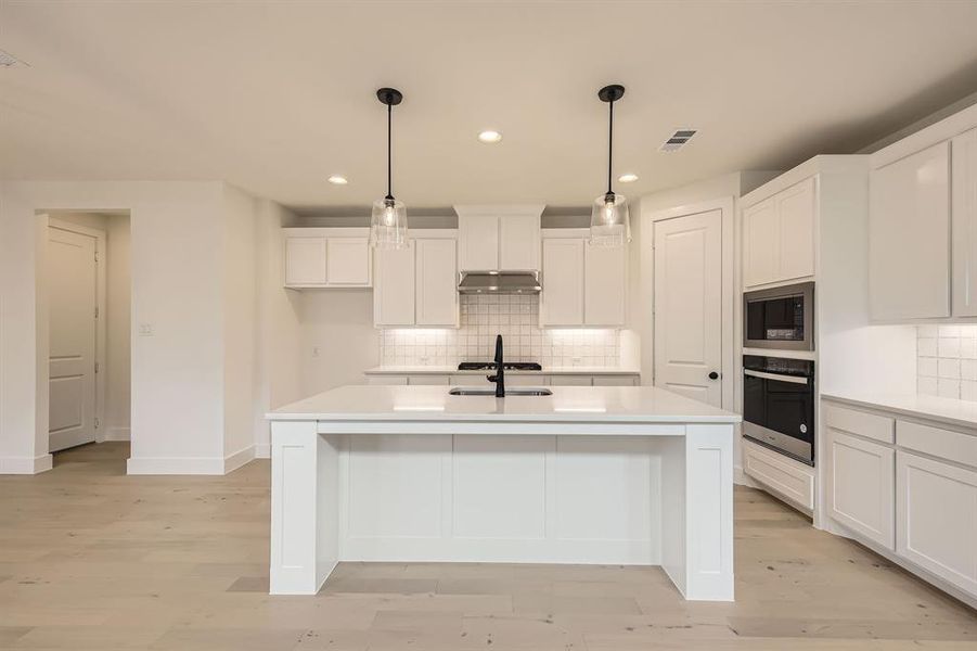 Kitchen with tasteful backsplash, stainless steel appliances, recessed lighting, white cabinetry, and an island with sink Kitchen with tasteful backsplash, stainless steel appliances, recessed lighting, white cabinetry, and an island with sink