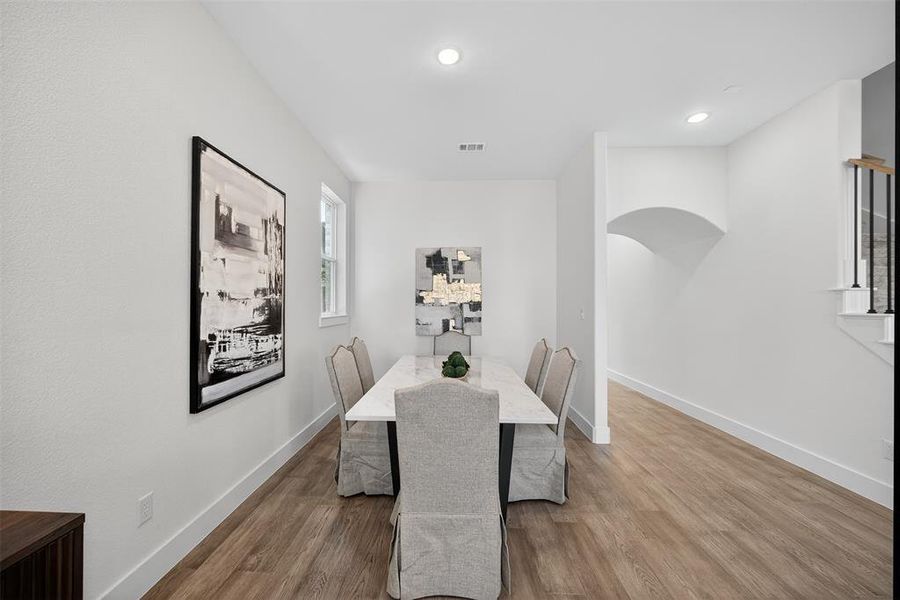 Dining space with wood finished floors, arched walkways, and recessed lighting Dining space with wood finished floors, arched walkways, and recessed lighting
