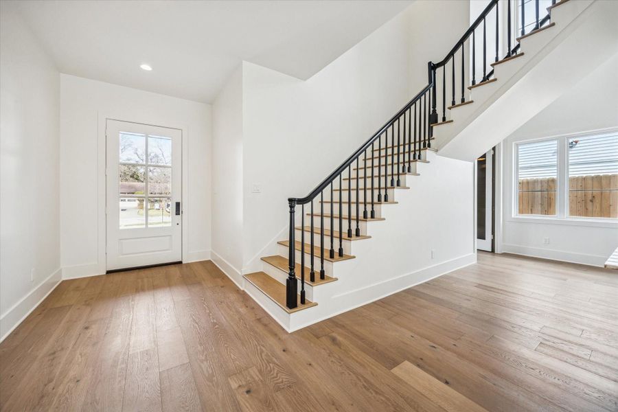Welcoming front entry with engineered hardwood flooring, natural light, and clean modern trim detail sets the tone for this custom Harvard Homes build in Oak Forest.