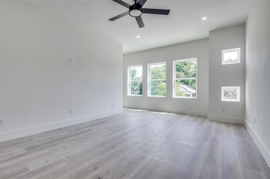 Empty room with healthy amount of natural light, ceiling fan, light wood-type flooring, and recessed lighting Empty room with healthy amount of natural light, ceiling fan, light wood-type flooring, and recessed lighting