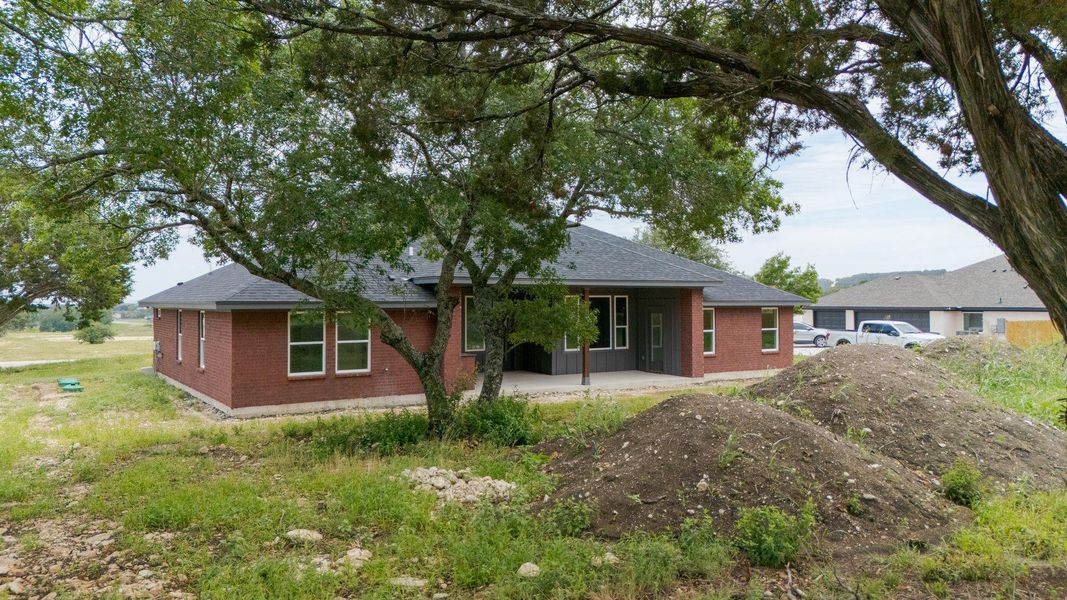 View of front of property featuring brick siding, a patio, and a shingled roof