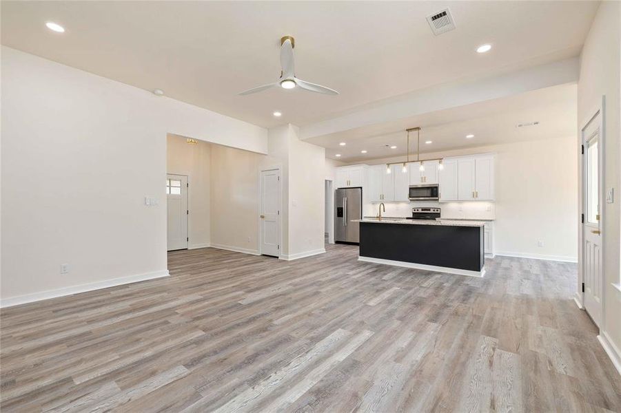 Unfurnished living room featuring ceiling fan, recessed lighting, and light wood-style flooring Unfurnished living room featuring ceiling fan, recessed lighting, and light wood-style flooring