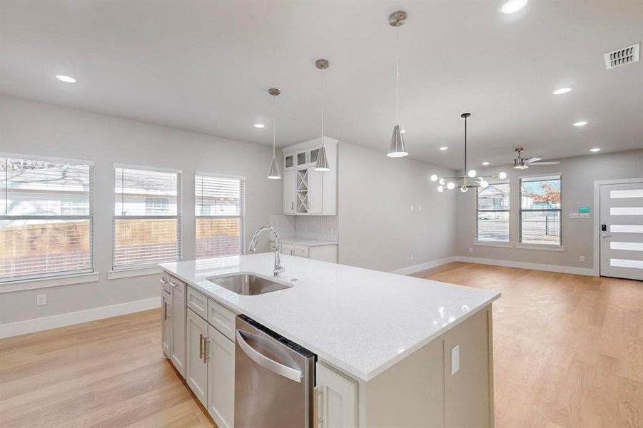 Kitchen with white cabinetry, dishwasher, sink, light hardwood / wood-style flooring, and decorative light fixtures