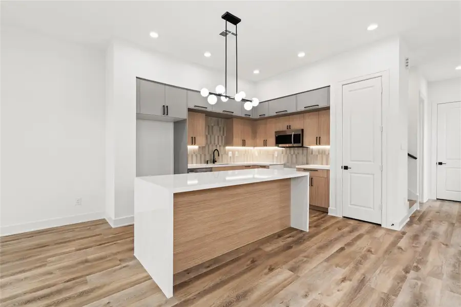 The kitchen is a true centerpiece, featuring a large island and a sleek, contemporary design that feels both stylish and functional. The open layout and modern lighting make it perfect for entertaining or everyday living.