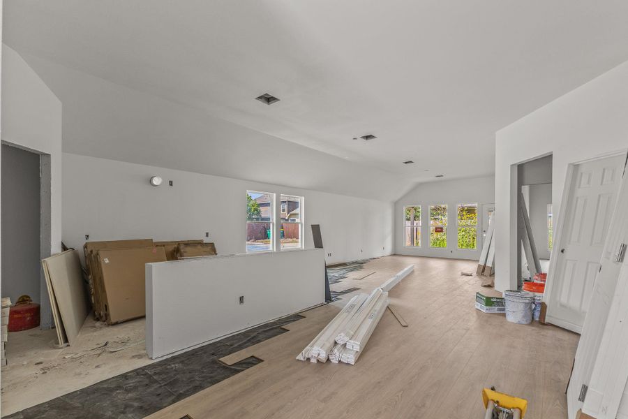 A spacious, naturally illuminated room featuring newly installed hardwood flooring.