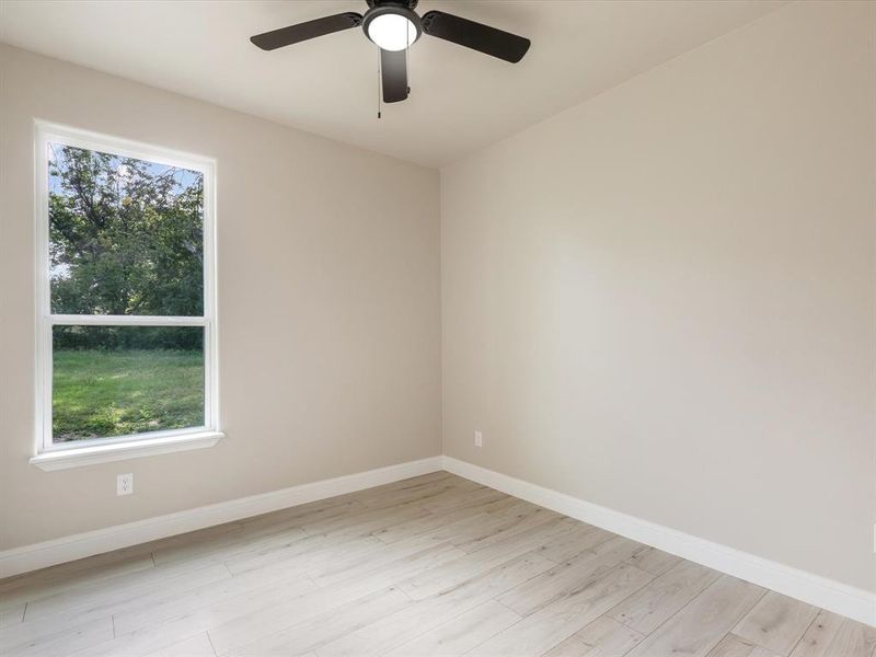 Unfurnished room with healthy amount of natural light, light wood-style floors, and a ceiling fan Unfurnished room with healthy amount of natural light, light wood-style floors, and a ceiling fan