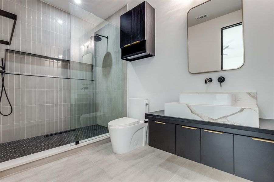 Bathroom featuring walk in shower, vanity, toilet, and tile floors