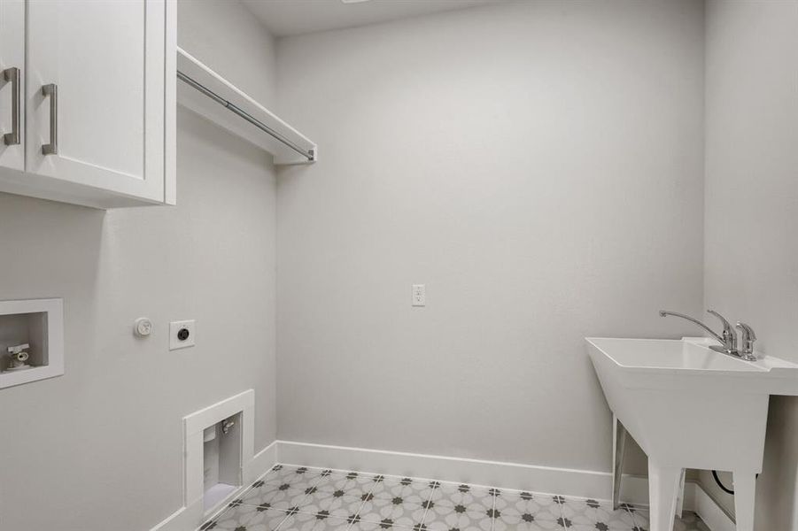 Utility room featuring patterned tile flooring, white shaker cabinetry, a hanging rod, a utility sink with a chrome faucet, and appliance hookups