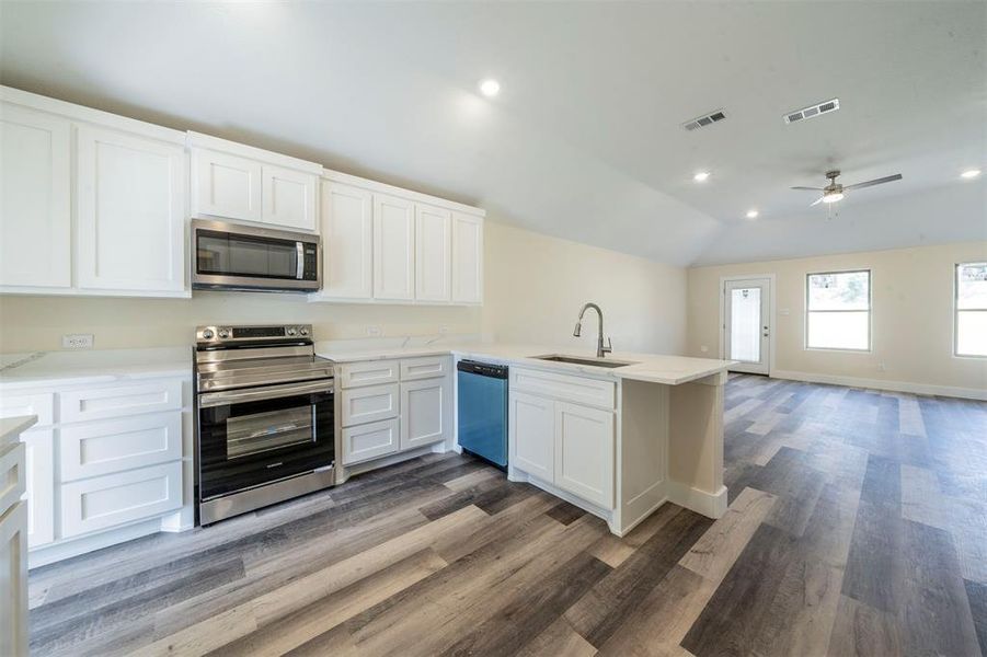 Kitchen featuring visible vents, appliances with stainless steel finishes, open floor plan, a sink, and a peninsula