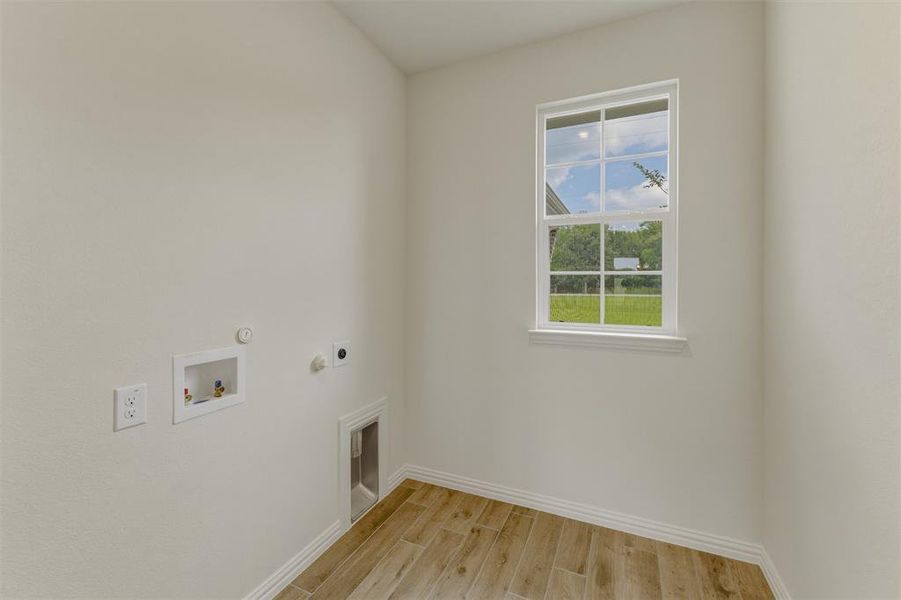 Utility area featuring wood-finish flooring, a white trim window, and white wall paint Utility area featuring wood-finish flooring, a white trim window, and white wall paint
