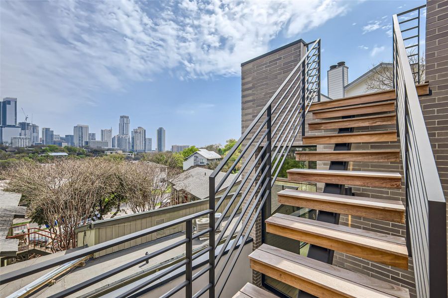 Ascend to panoramic city views from this sleek rooftop patio featuring modern wood and metal staircases. Ascend to panoramic city views from this sleek rooftop patio featuring modern wood and metal staircases.