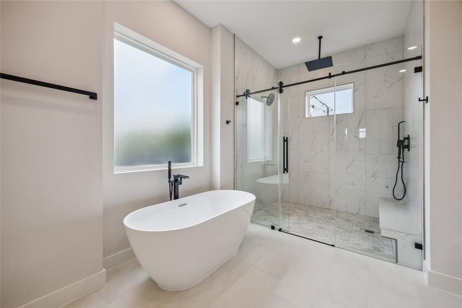 The primary bath features dual vanities, a freestanding soaking tub, and a glass-enclosed walk-in shower with full-height tile surround. Clean lines, modern fixtures, and oversized windows keep the space feeling bright and polished throughout. The primary bath features dual vanities, a freestanding soaking tub, and a glass-enclosed walk-in shower with full-height tile surround. Clean lines, modern fixtures, and oversized windows keep the space feeling bright and polished throughout.