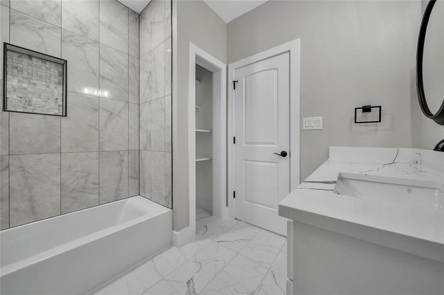 Bathroom featuring vanity, tiled shower / bath, and tile patterned flooring